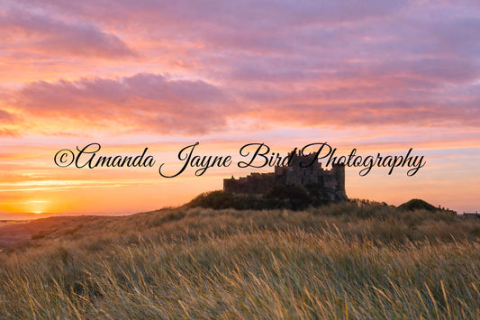 Bamburgh Castle rising through the dunes at sunrise